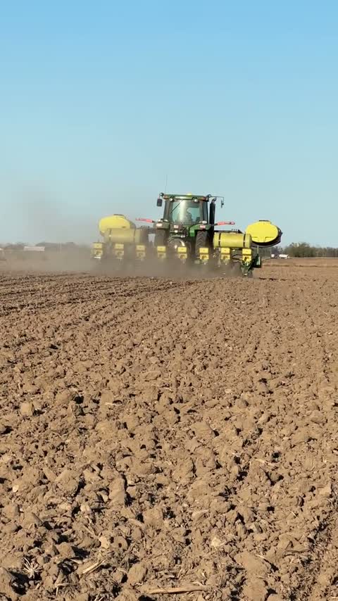Tractor and planter working a dusty spring field